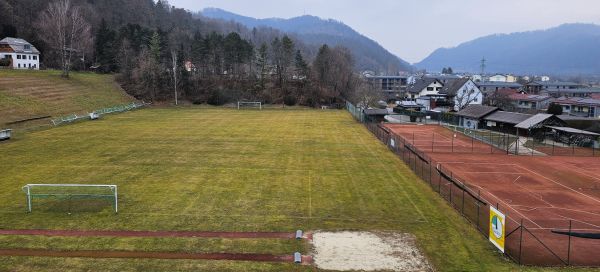 Soccer pitch and tennis court with mountains and forests in the background.