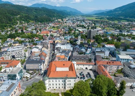 Spittal an der Drau aus der Vogelperspektive. um die Stadt herum sind Berge mit Wäldern.