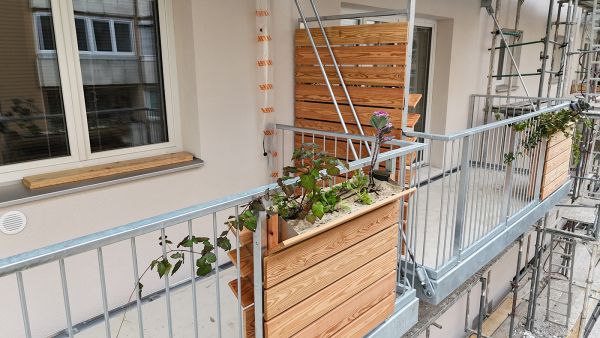 Balkon von außen, mit begrüntem, vertikalem Blumenkasten.