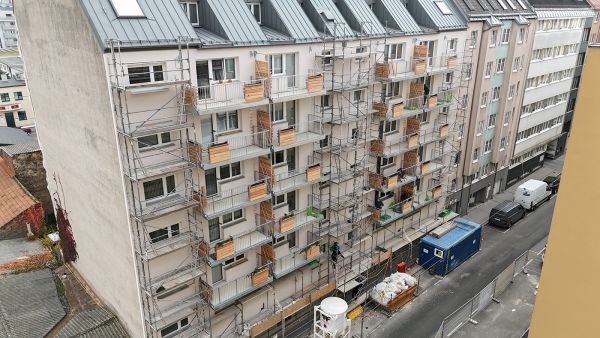 Mehrstöckiges Gebäude mit Gerüst an der Fassade, von schräg oben fotografiert.