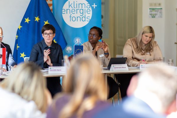 Personen sitzen um einen Tisch und reden miteinander