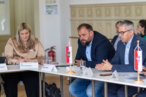 Personen sitzen um einen Tisch und sprechen miteinander