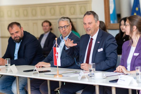 Personen sitzen um einen Tisch und sprechen miteinander