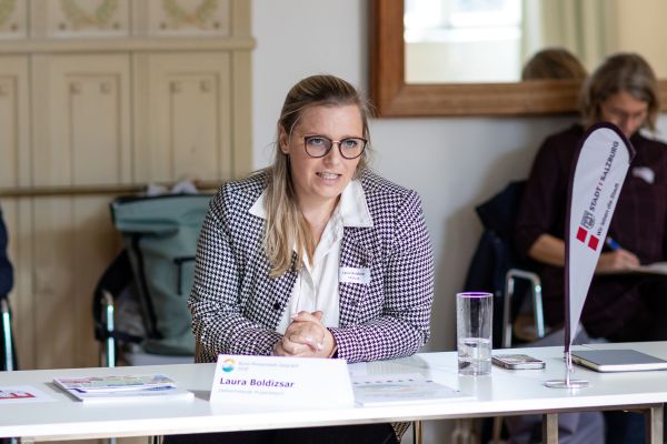 Personen sitzen um einen Tisch und sprechen miteinander