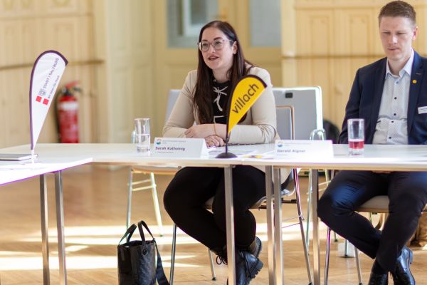 Personen sitzen um einen Tisch und sprechen miteinander