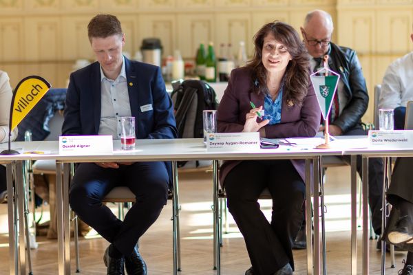 Personen sitzen um einen Tisch und sprechen miteinander