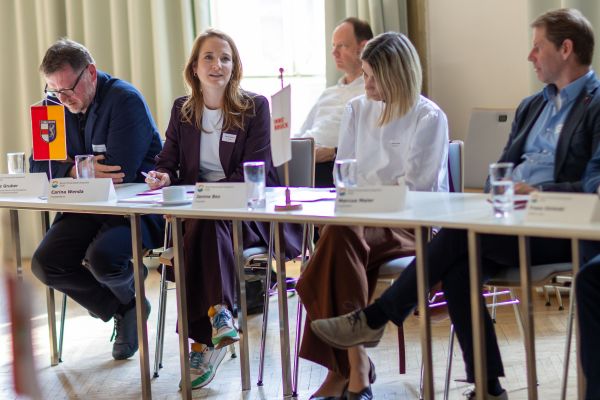 Personen sitzen um einen Tisch und sprechen miteinander