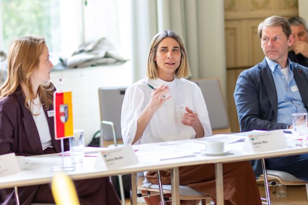 Personen sitzen um einen Tisch und sprechen miteinander