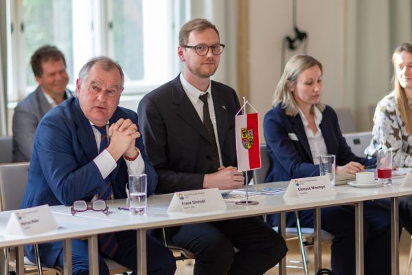 Personen sitzen um einen Tisch und sprechen miteinander