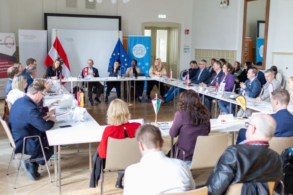 Ca. 30 Personen sitzen in einer Runde beisammen und diskutieren