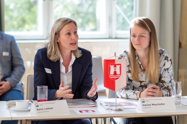 Personen sitzen um einen Tisch und sprechen miteinander