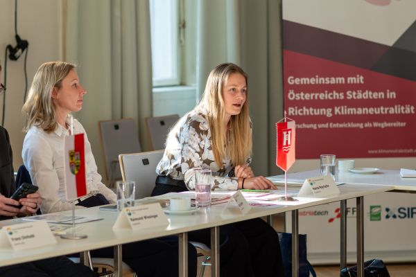 Personen sitzen um einen Tisch und sprechen miteinander