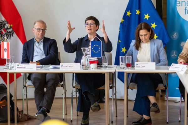 Drei Personen sitzen an einem Tisch und sprechen