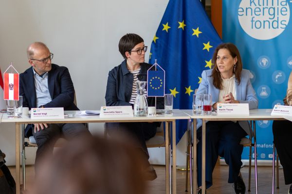 Drei Personen sitzen an einem Tisch und sprechen