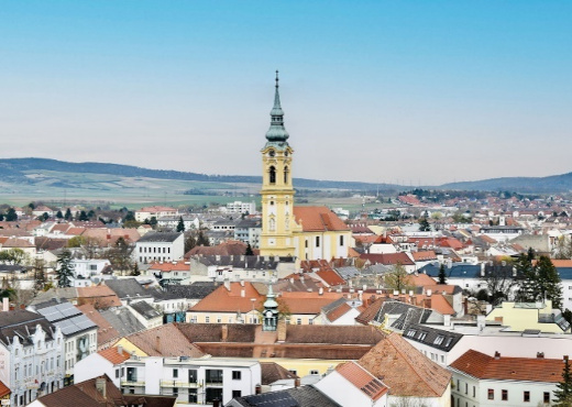 Vogelperspektive Stockerau, mittig steht eine gelbe Kirche rundherum Häuser.