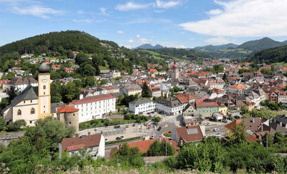 Eine Stadt von oben, im Hintergrund ein grüner Hügel